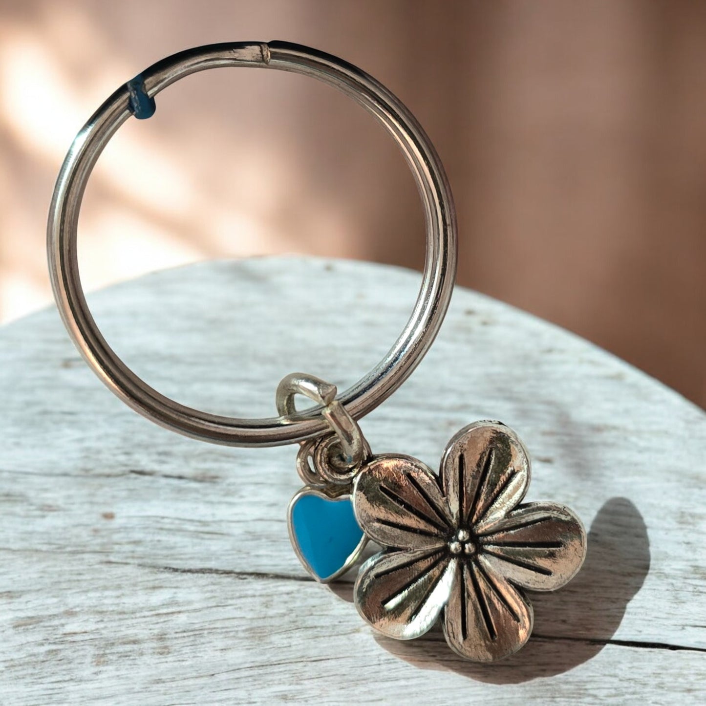 Silver keychain with a floral charm on a green marble surface to be used with Boho Crochet bag