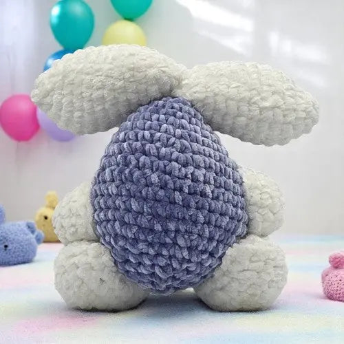 crochet blue bunny with large white ears and feet showing his back