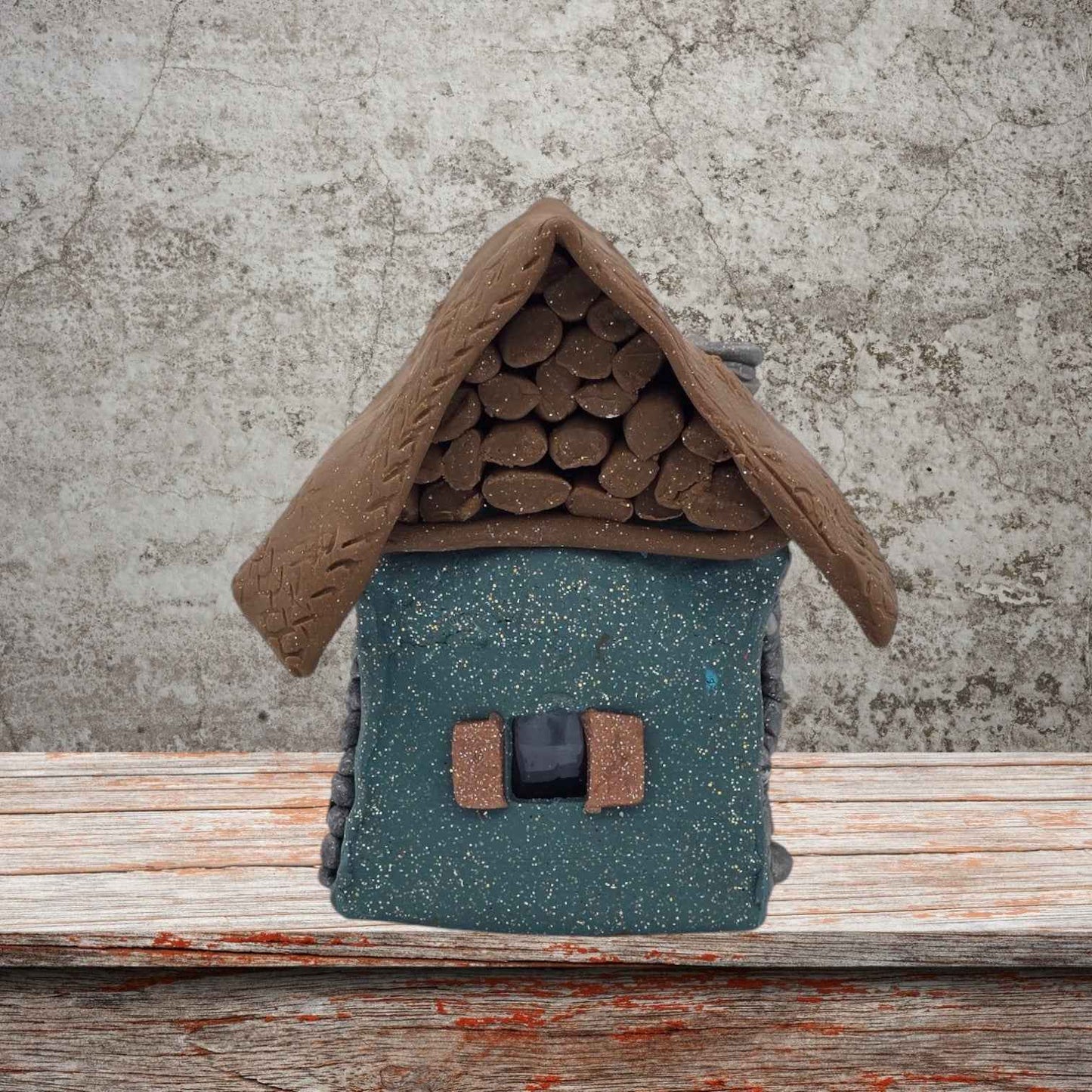 A small house featuring a sloped roof and a front door, set against a simple background.