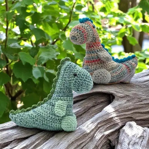 TWO DINOSAUR CROCHET TOY SITTING ON A LOG