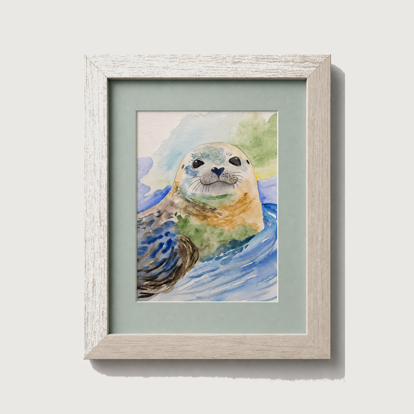 Framed watercolor art print of a seal in blue water, set in a light wood frame with a pale green mat, shown against a neutral light gray background.