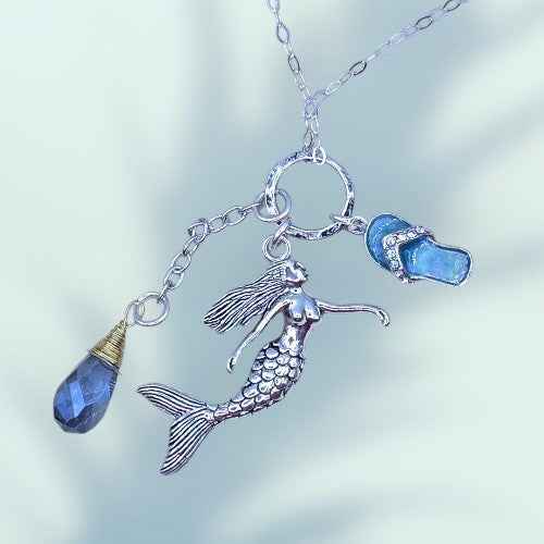 A mermaid necklace featuring a shimmering blue crystal pendant, elegantly designed for ocean-inspired jewelry lovers.