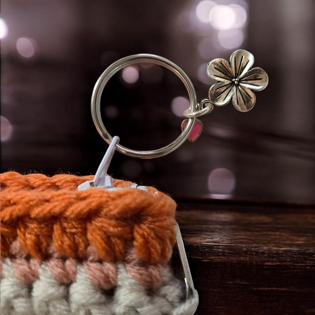 Silver keychain with a flower charm on a wooden surface used with a boho crochet bag