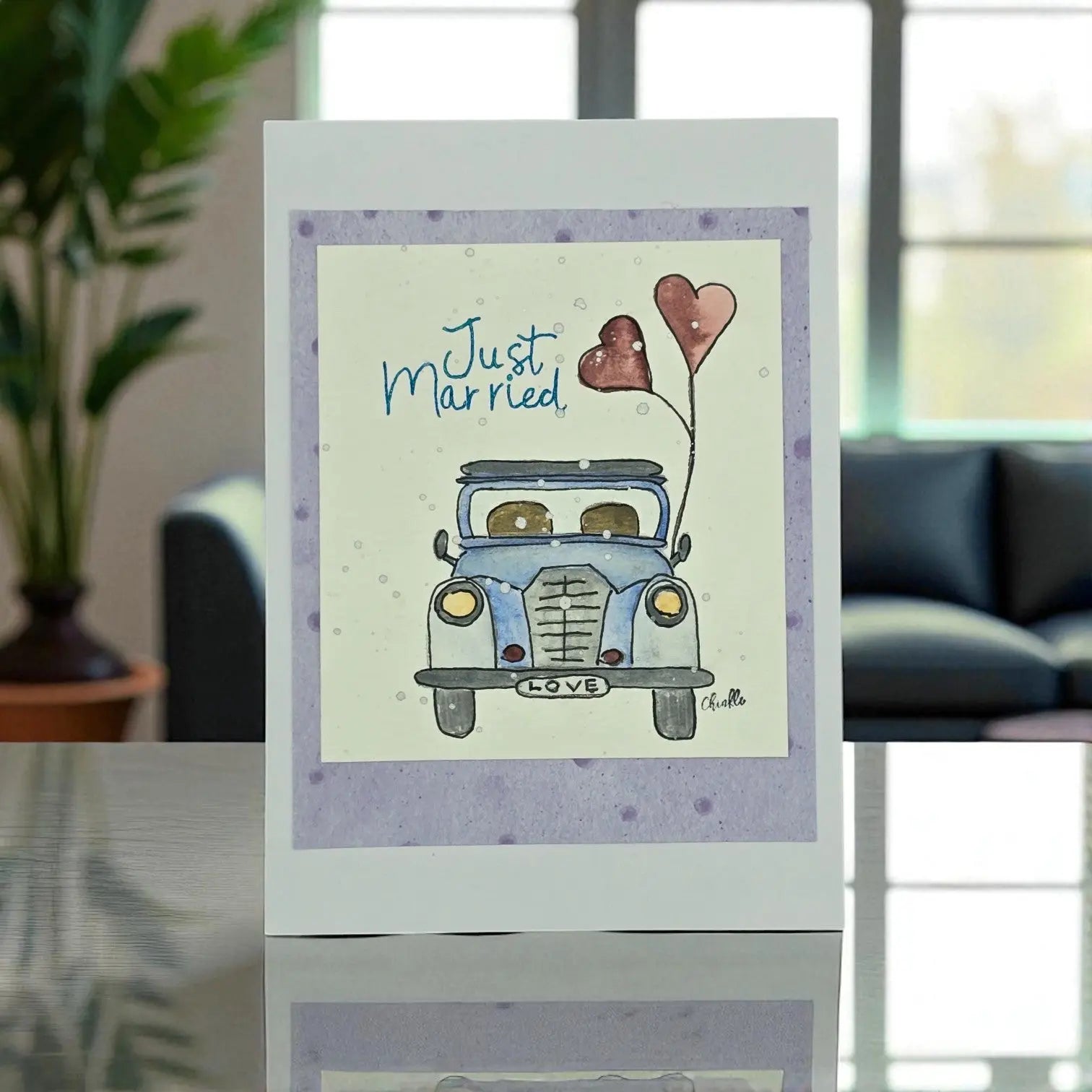 A wedding card featuring a decorative car with a balloon in the center, symbolizing celebration and joy.