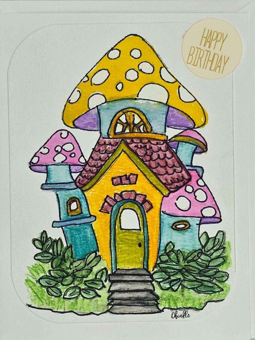 A whimsical birthday card featuring a colorful mushroom house surrounded by flowers and butterflies.