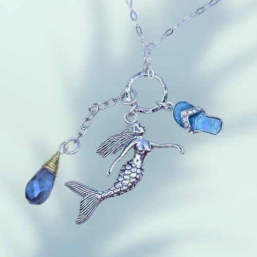 A mermaid necklace featuring a shimmering blue crystal pendant, elegantly designed for ocean-inspired jewelry lovers.