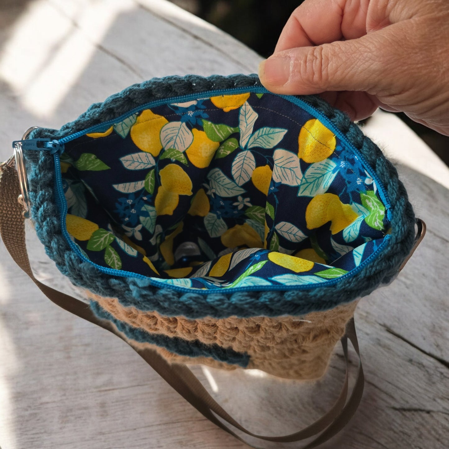 Hand holding a boho crochet fabric pouch with lemon pattern on a dark surface