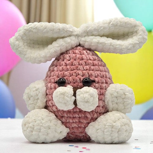 crochet pink bunny with  large white ears and feet facing front