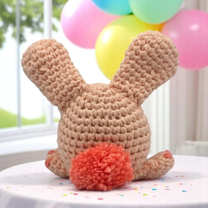 peach bunny head with big ears facing his back to you showing you his tail