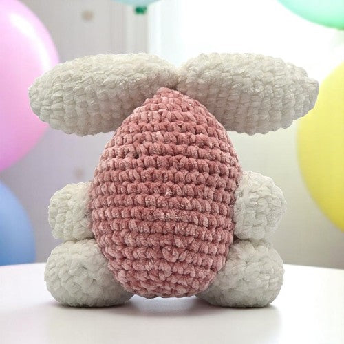 crochet pink bunny with  large white ears and feet showing his back