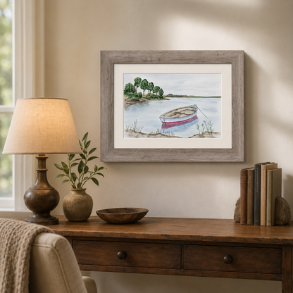 A framed watercolor painting of a small red and white boat on a lake, displayed on a beige wall above a wooden console table with a lamp, books, and a bowl.