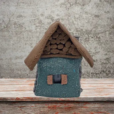 A small house featuring a sloped roof and a front door, set against a simple background.