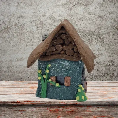 A small house featuring a sloped roof and a front door, set against a simple background.