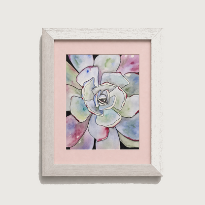 Framed watercolor art print of a succulent flower with pastel blue, green, pink, and purple petals, set in a light pink mat and a distressed white frame against a light gray background.
