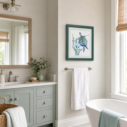 A framed art print of a blue and green sea turtle on a white background, styled in a dark green frame on a beige wall in a modern bathroom setting.