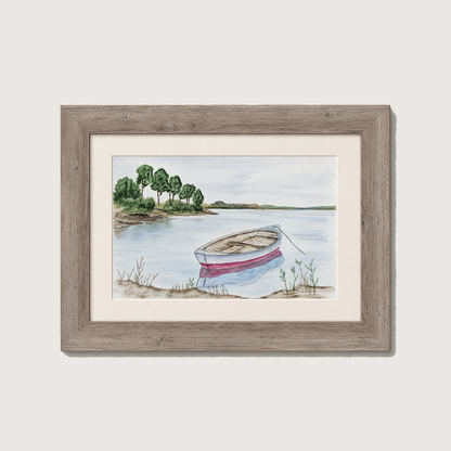 A framed watercolor landscape print showing a small rowboat on calm water near a tree-lined shore, set in a rustic gray wooden frame with a white mat against a light gray background.