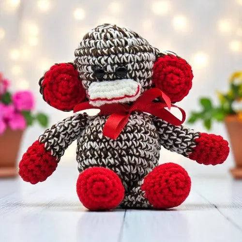 a cute crochet brown and white monkey with red hand feet and ears facing forward