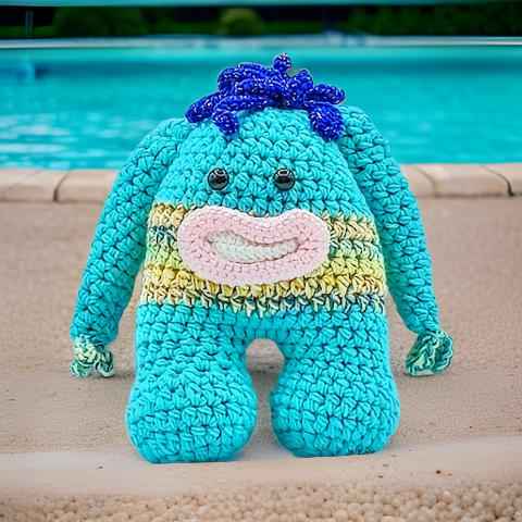A crocheted toy monster featuring a blue bod with vibrant  blue hair, showcasing a playful and colorful design. 