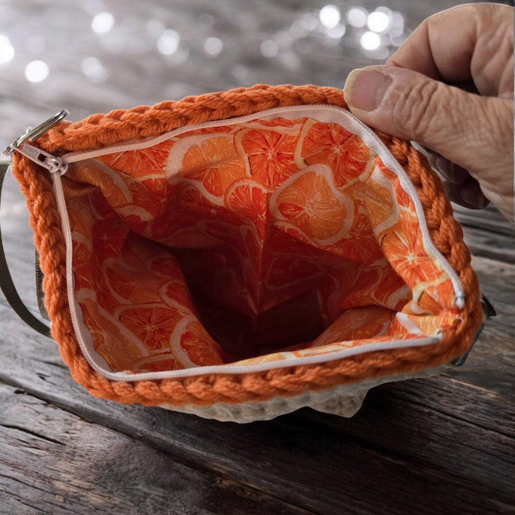 Orange fabric lining with zipper, held by a hand on a neutral background as part of a boho crochet bag