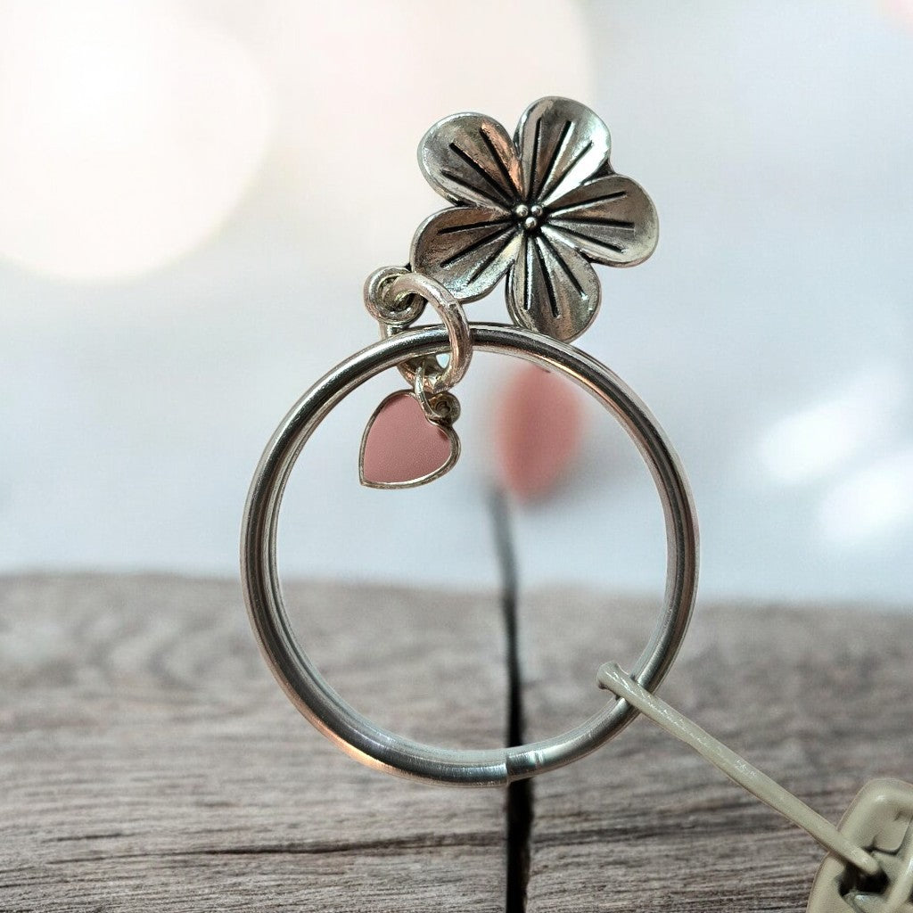 Silver keychain with a flower and heart charm on a wooden surface to be used with boho crochet bag