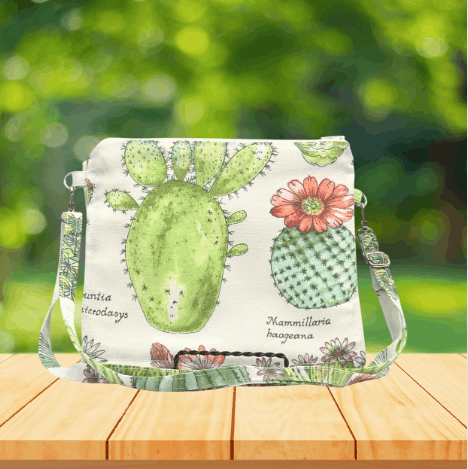 Handmade crossbody purse with cactus print, featuring two zippered pockets and one inner slip pocket.