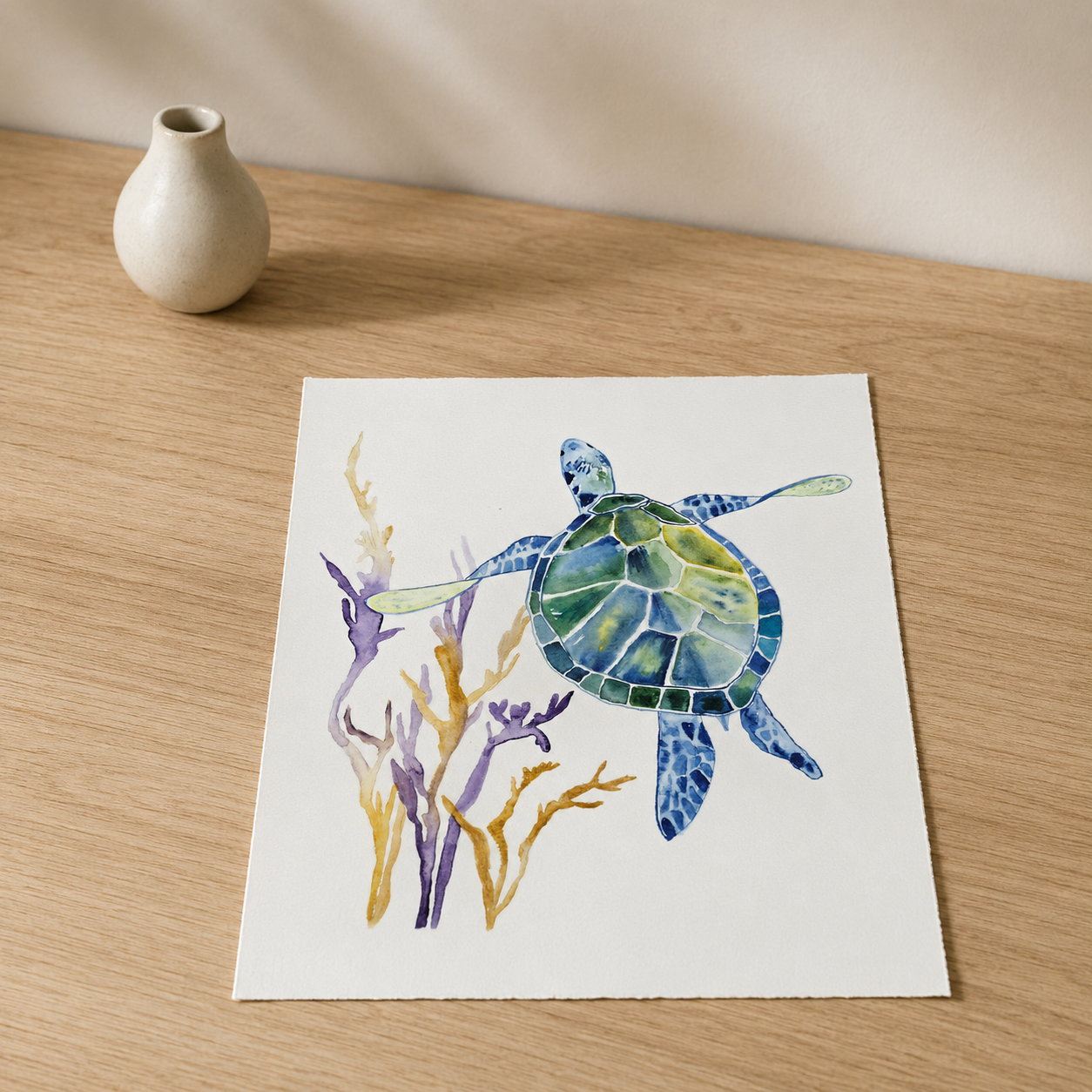 A square art print featuring a watercolor painting of a sea turtle swimming among purple and gold seaweed, displayed on a light wood tabletop next to a small beige ceramic vase.