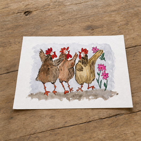A square watercolor art print depicting three brown chickens with red combs standing among pink flowers, placed on a rustic wooden surface.