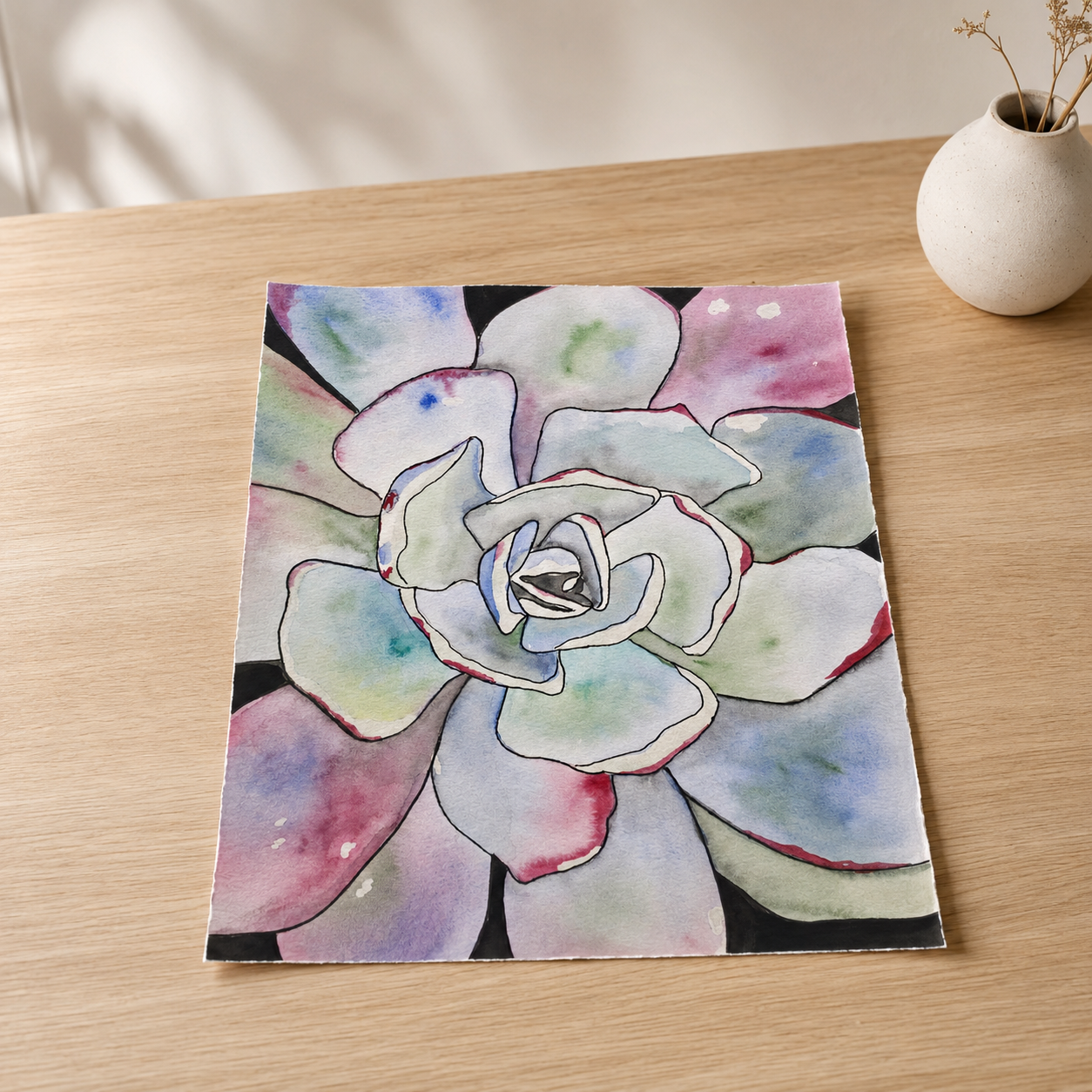 A square art print featuring a watercolor painting of a succulent flower, styled on a light wood tabletop next to a small white ceramic vase.