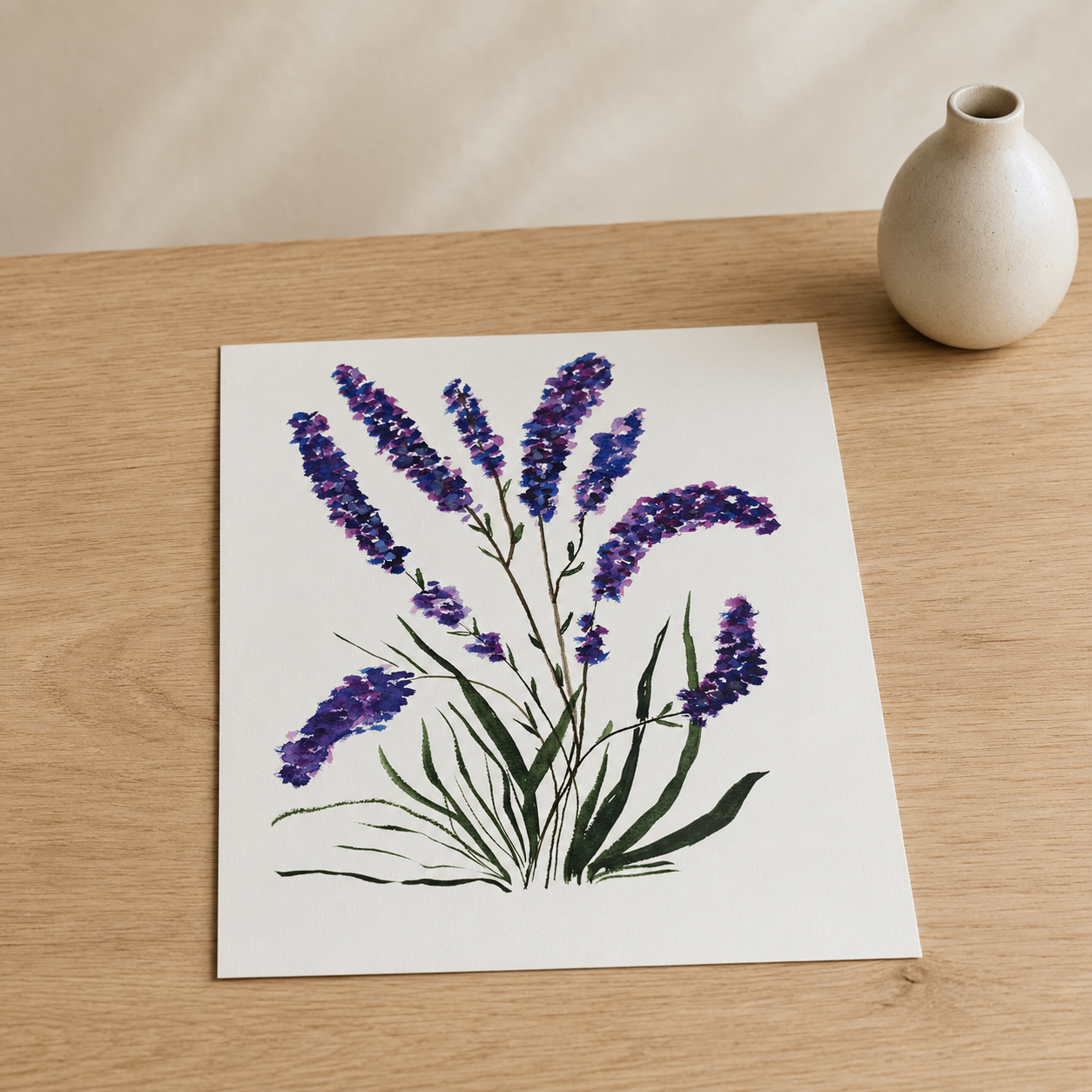 A square art print featuring a watercolor illustration of purple lavender flowers with green stems and leaves, displayed on a light wood tabletop next to a small beige ceramic vase.