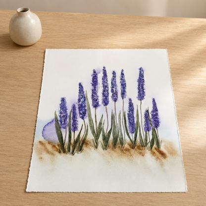 A square watercolor painting of purple hyacinth flowers with green stems and brown ground, displayed on a light wood tabletop next to a small ceramic vase.