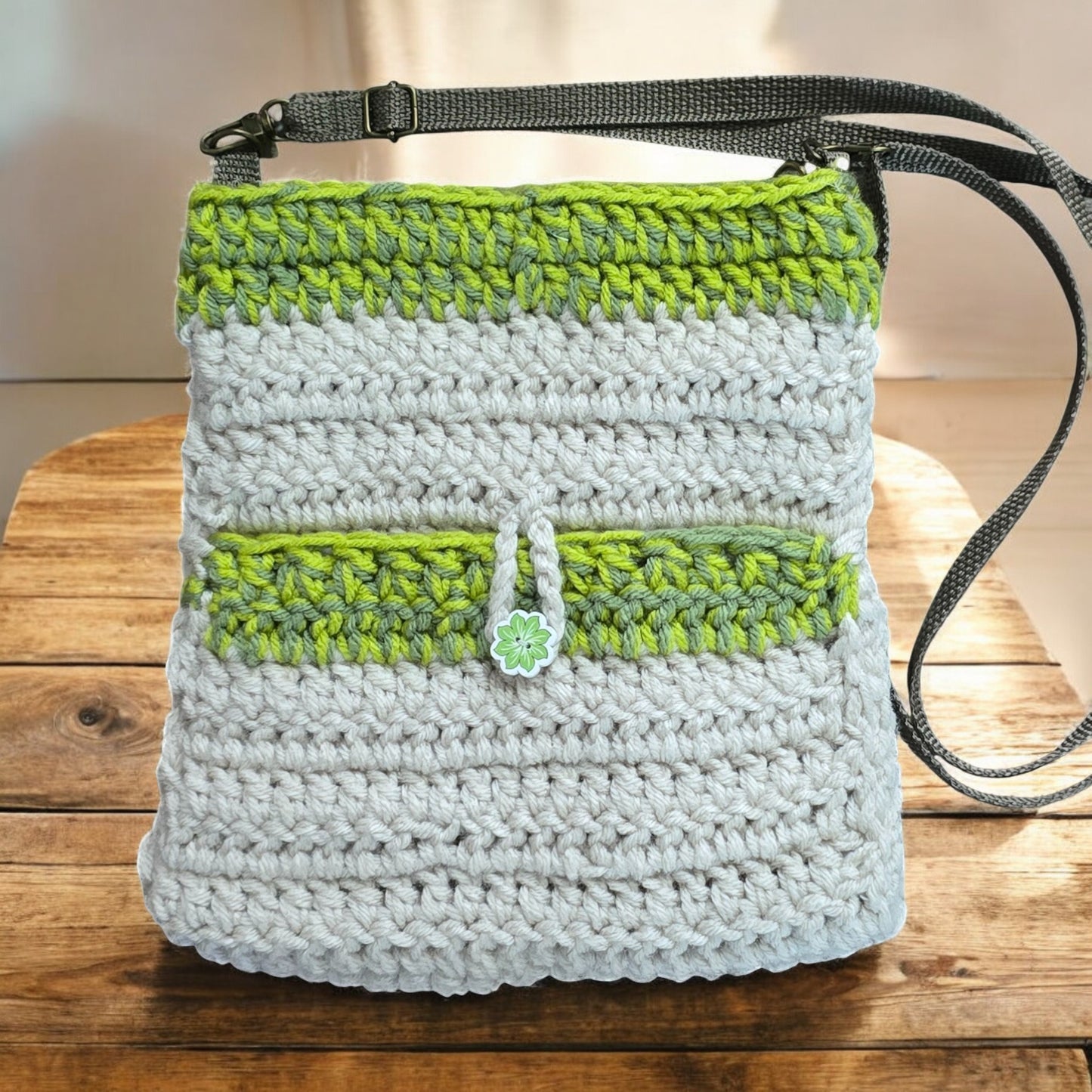 Boho Crochet bag with green and white pattern on a wooden surface with blurred greenery in the background