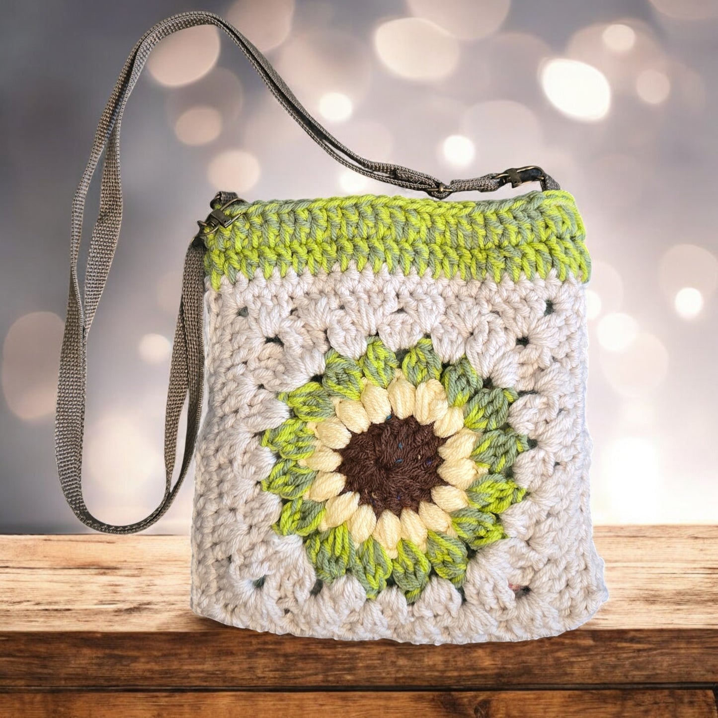 Bohon Crochet bag with sunflower design on a wooden surface with a blurred green background
